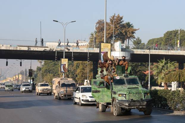 Rebel fighters sit on a vehicle, in Damascus