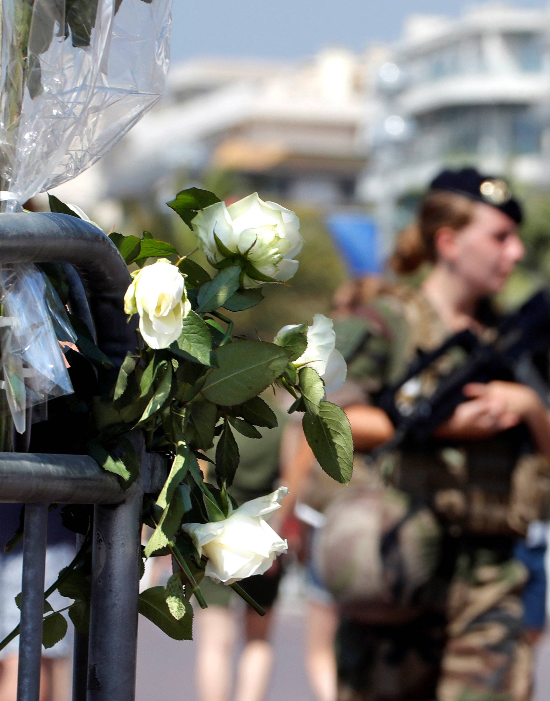 Armed French soldiers patrol near a bouquet of white roses left as part of the commemorations of last year's July 14 fatal truck attack on the Promenade des Anglais in Nice