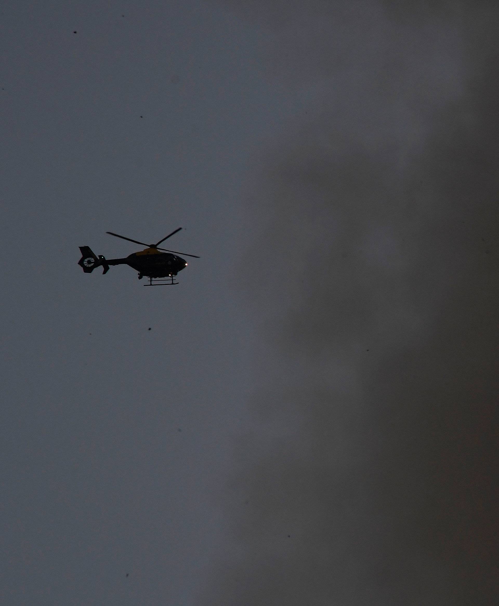A helicopter is seen as smoke billows as firefighters  deal with a serious fire in a tower block at Latimer Road in West London