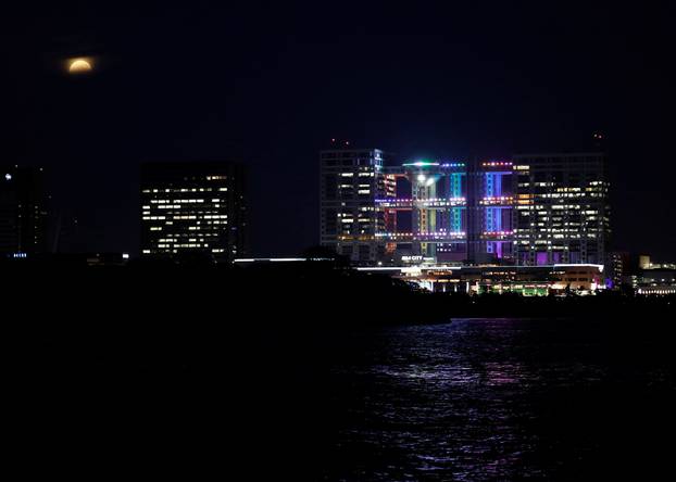 A supermoon, the biggest and brightest full moon of the year, rises through clouds above Odaiba of Tokyo