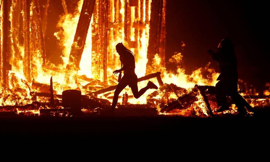 Burning Man participant runs into the flames of the "Man Burn" at the Burning Man arts and music festival in the Black Rock Desert of Nevada