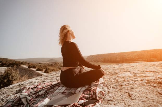 Woman Meditating on a Mountaintop with a Laptop