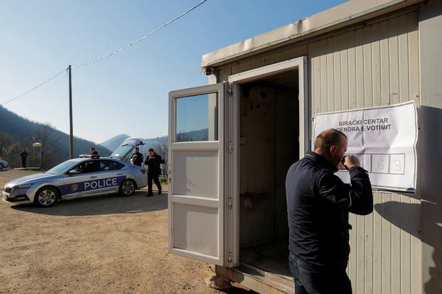 Kosovar police officers stand guard next to a container used as an alternative voting center, in Zubin Potok