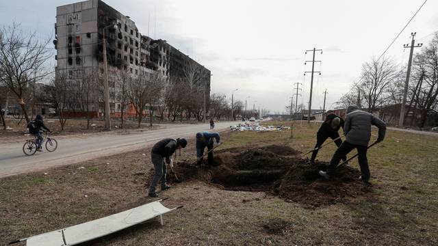 People dig a grave in the besieged city of Mariupol