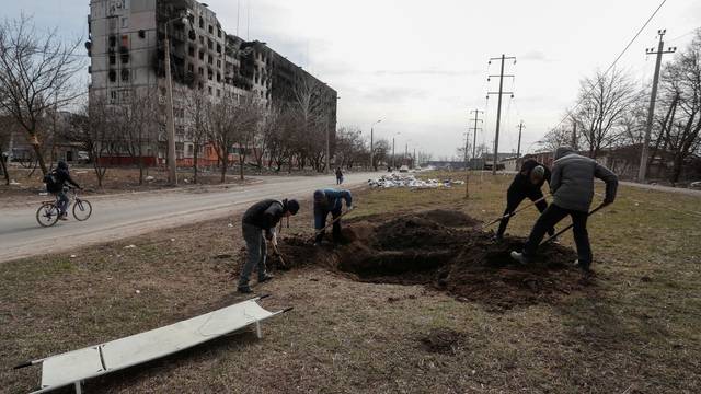 People dig a grave in the besieged city of Mariupol