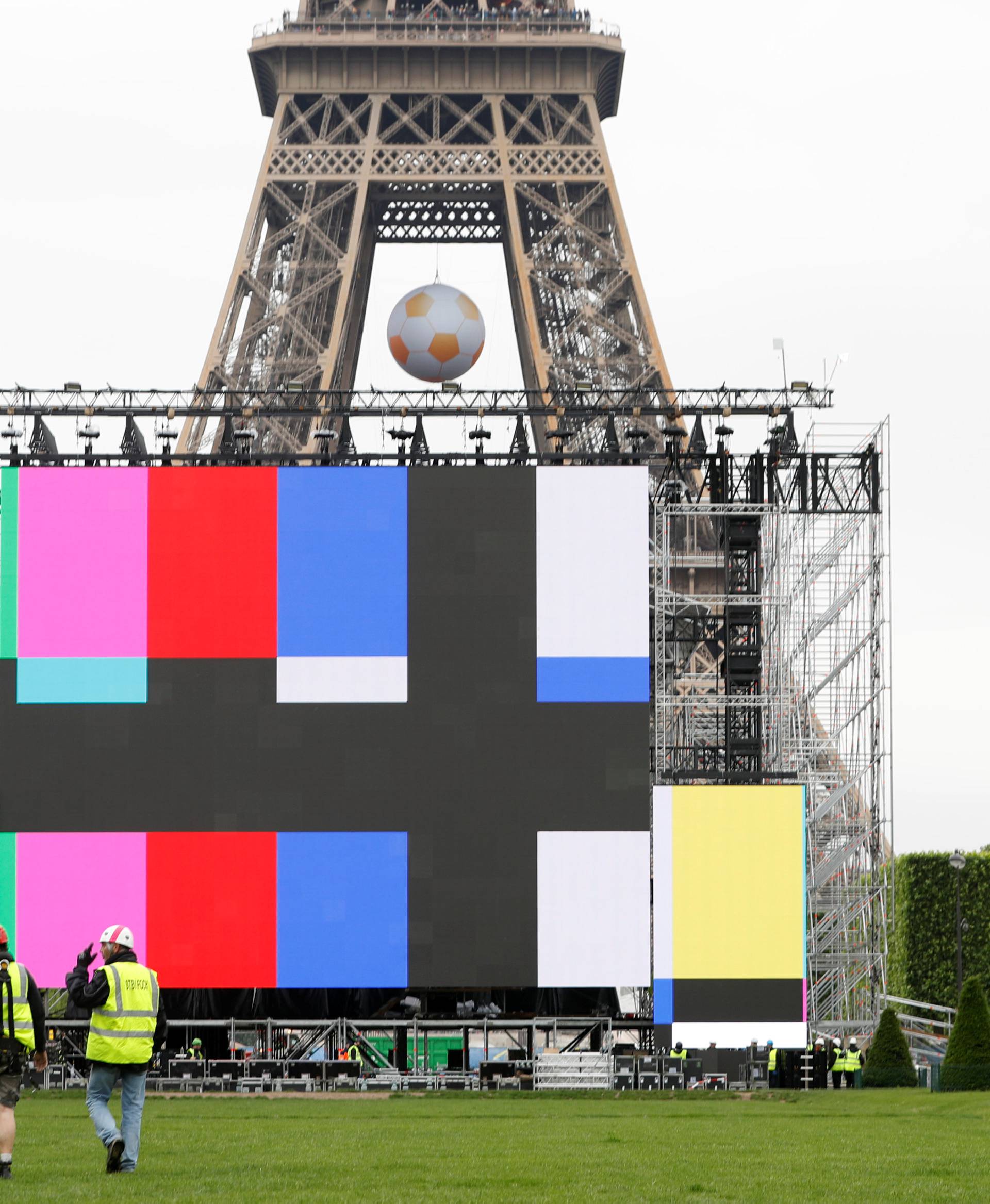 Workers install a giant screen at a fan zone near the Eiffel Tower before the start of the UEFA 2016 European Championship in Paris