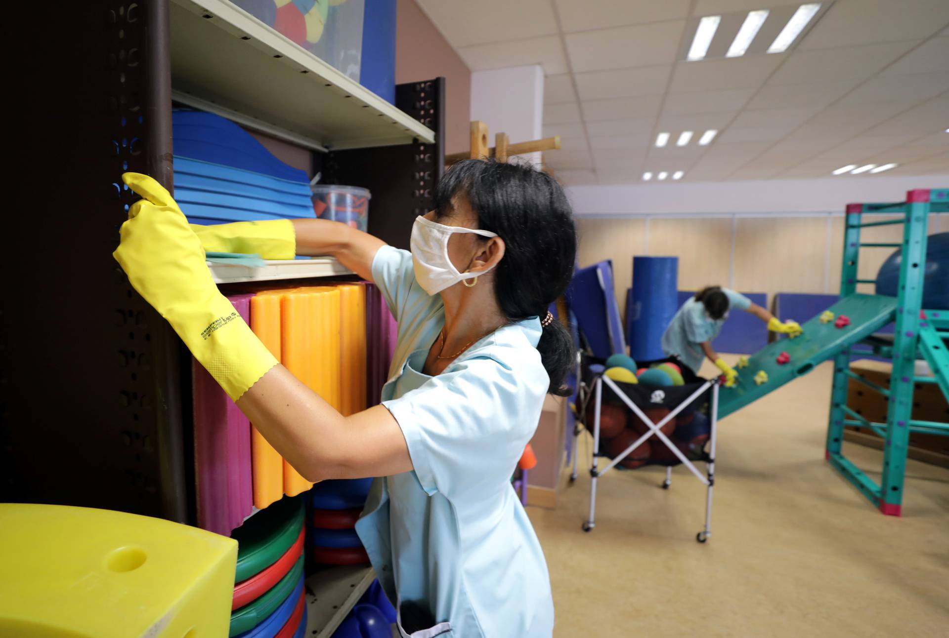 Municipal employees, wearing protective face masks, clean a playroom at a primary school in Le Cannet
