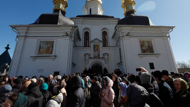 Believers pray while they block an entrance to a church at a compound of the Kyiv Pechersk Lavra monastery in Kyiv