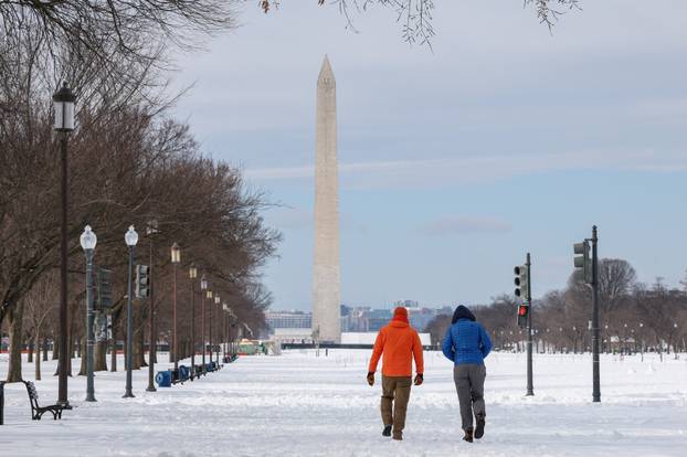 People walk along the National Mall, which is covered in snow, after a winter storm in Washington