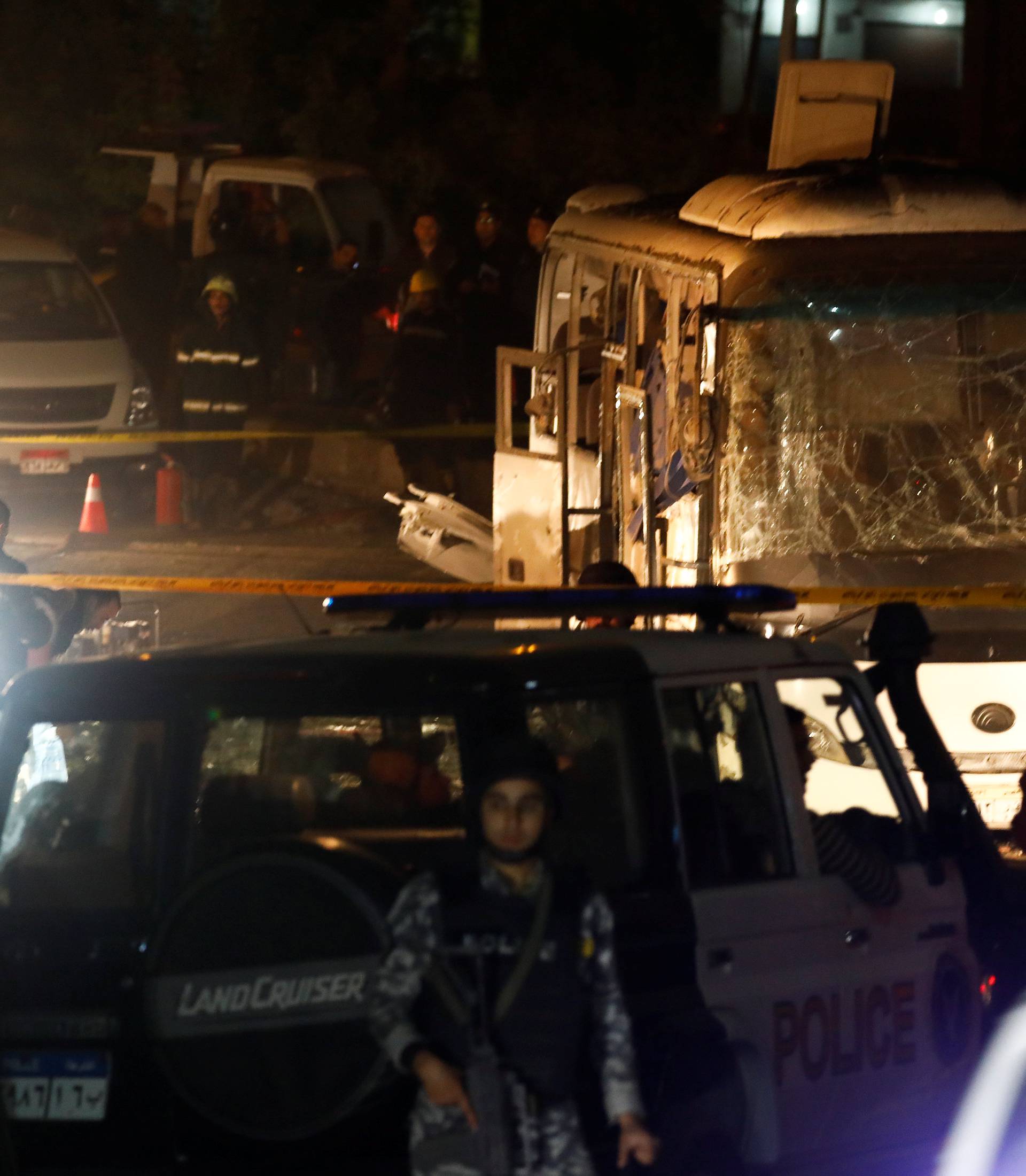 Police officers inspect a scene of a bus blast in Giza