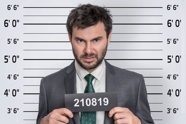 Mugshot of man in suit at police station