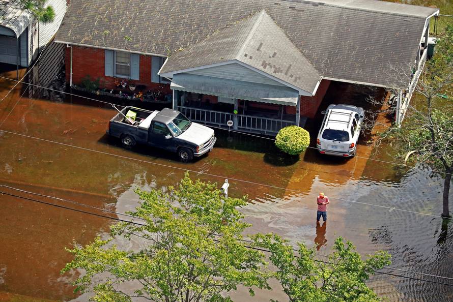 Man stands outside a flooded home caused by Hurricane Florence in Lumberton
