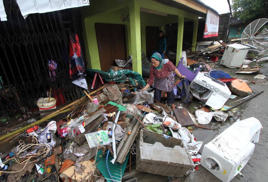 A local resident searches for her items after a tsunami hit at Sumur district in Pandeglang