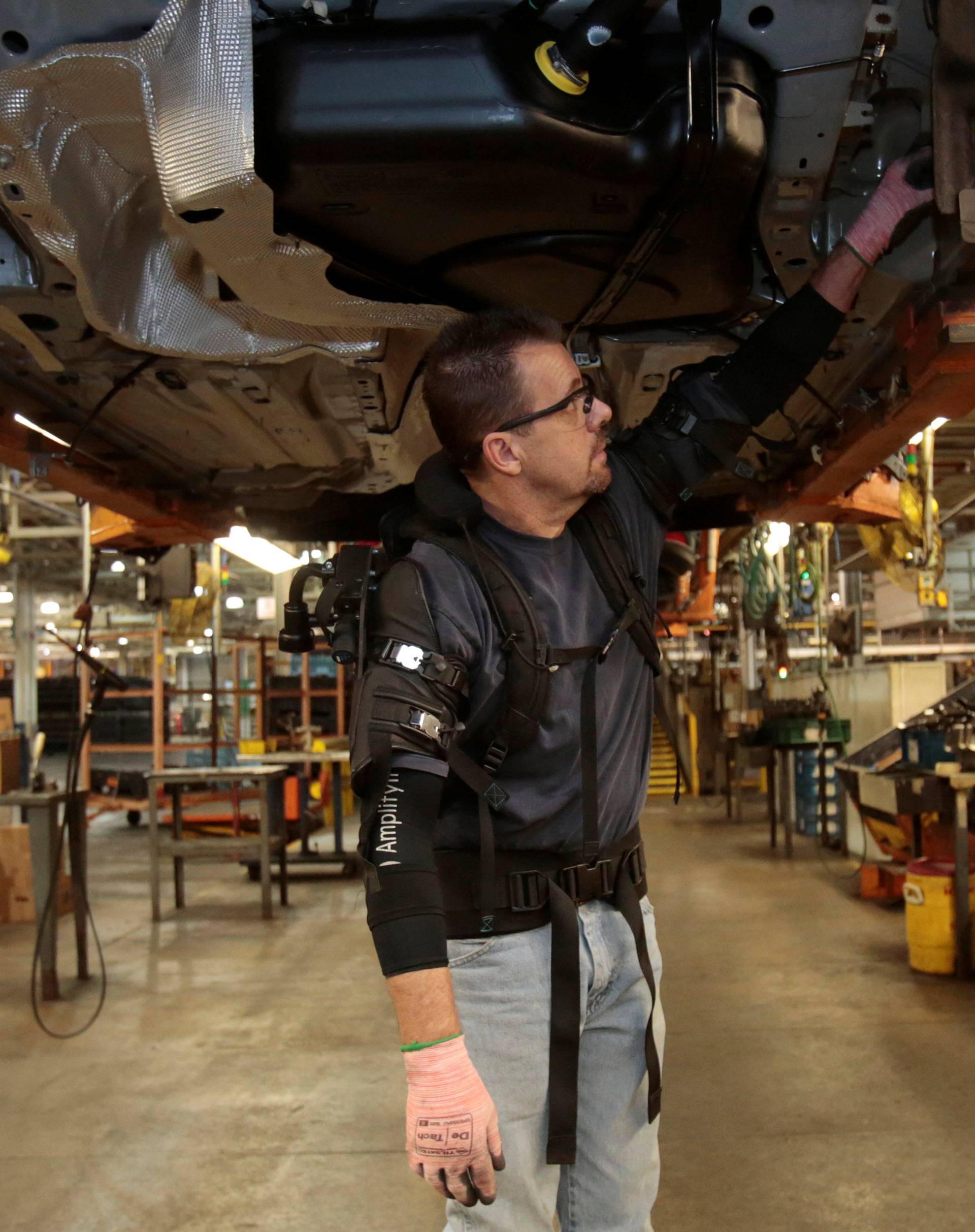 Ford Motor Co assembly worker Paul Collins wears a EksoVest as he works on the assembly line producing the Ford Focus and C-max at Wayne Assembly plant