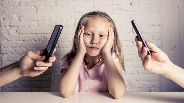 hands of network addict parents using mobile phone neglecting little sad ignored daughter bored