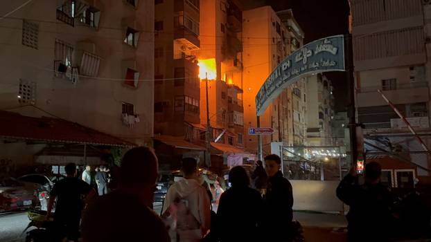 People gather near a building where a floor caught fire following an Israeli strike, in which the Israeli military said, it killed Hamas commander Hassan Farhat, in Sidon