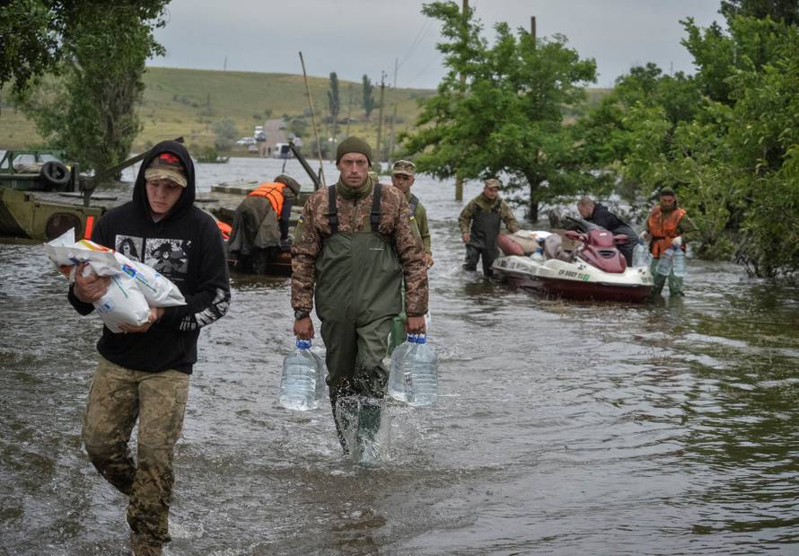 Ukrainian servicemen unload humanitarian aid for local residents after the Nova Kakhovka dam breached, in the flooded village of Afanasiivka