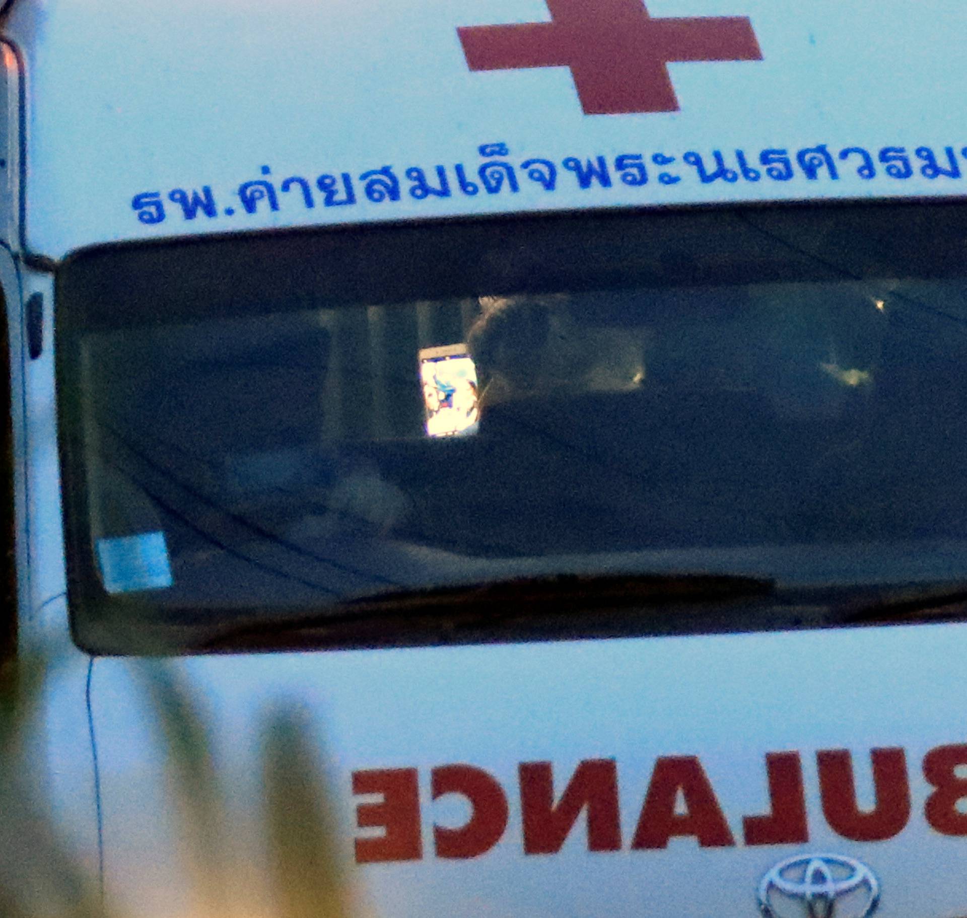 A person is seen using a mobile phone in an ambulance leaving from Tham Luang cave complex in the northern province of Chiang Rai