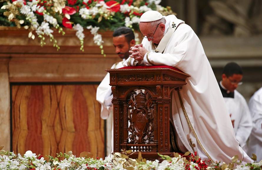 Pope Francis kneels as he leads the Christmas night Mass in Saint Peter's Basilica at the Vatican