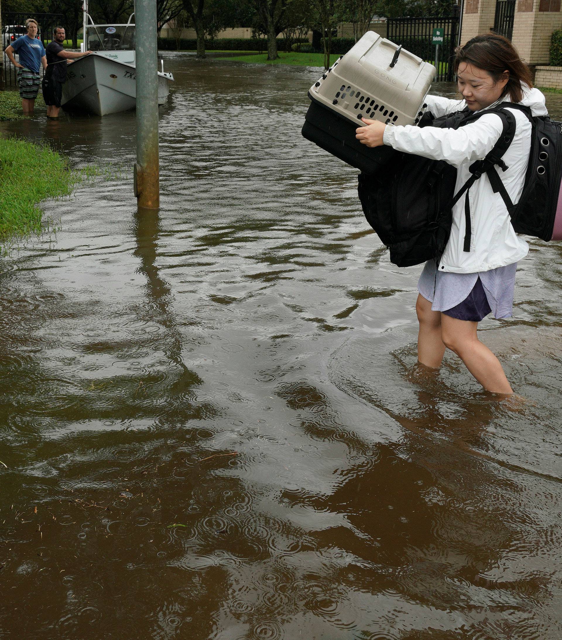 A woman holds a carrier with her pet after being evacuated by boat from the Hurricane Harvey floodwaters in Houston