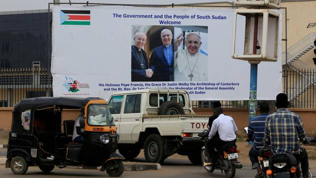 FILE PHOTO: Motorists drive past a billboard showing the preparations to welcome Pope Francis, Archbishop of Canterbury Justin Welby and Church of Scotland Moderator Iain Greenshields, ahead of their visit in Juba