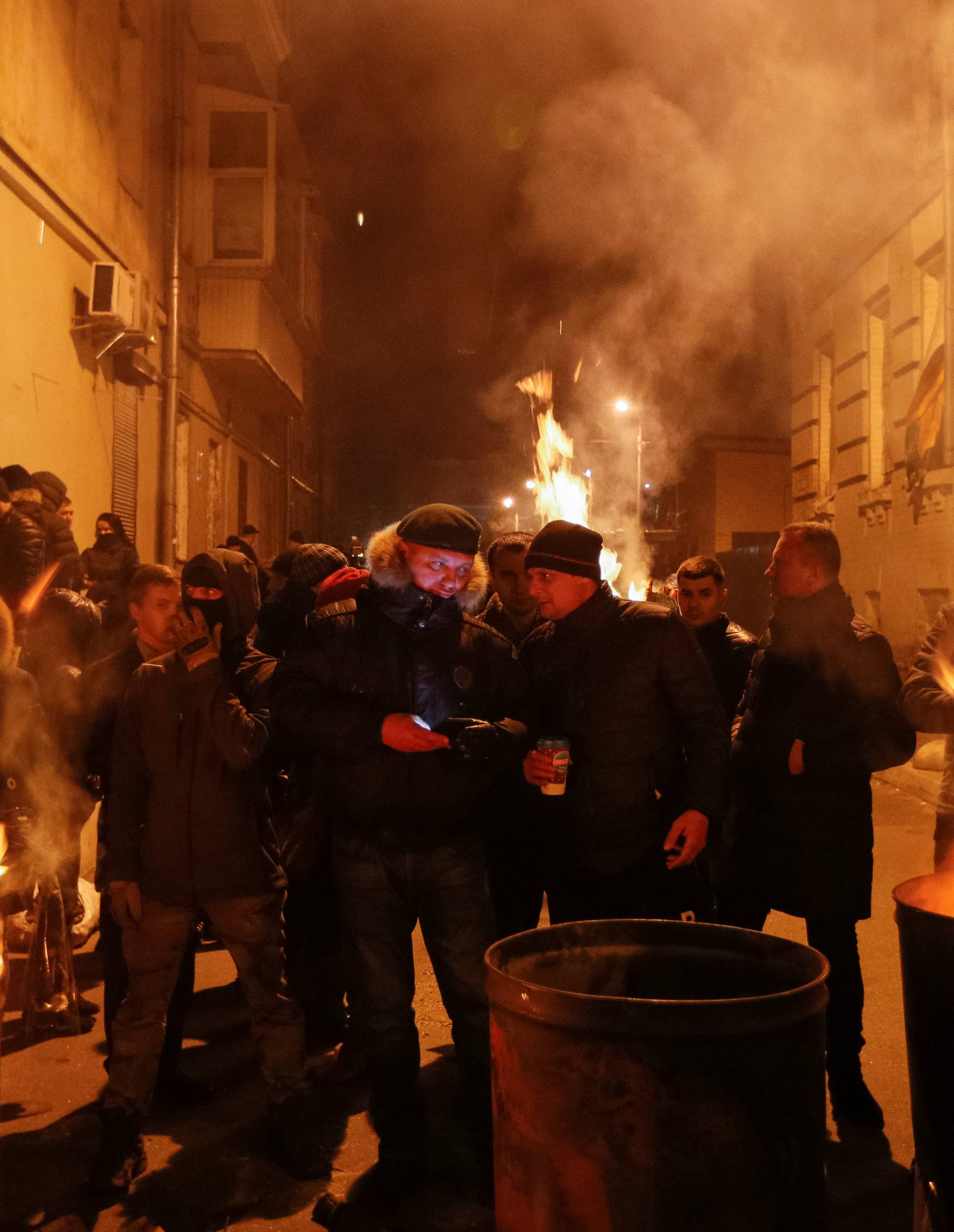 Supporters of former Georgian President Mikheil Saakashvili warm themselves at a bonfire near a temporary detention facility where Saakashvili was escorted after being detained in Kiev, Ukraine