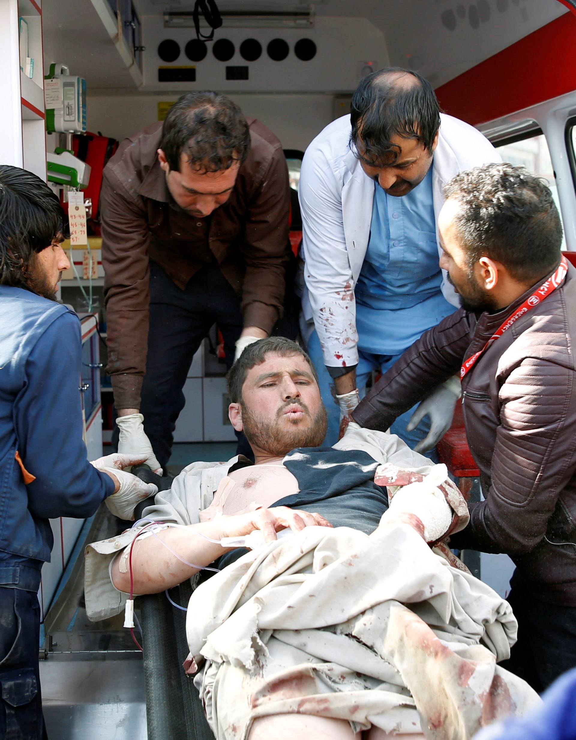 People carry an injured man to a hospital after a blast in Kabul