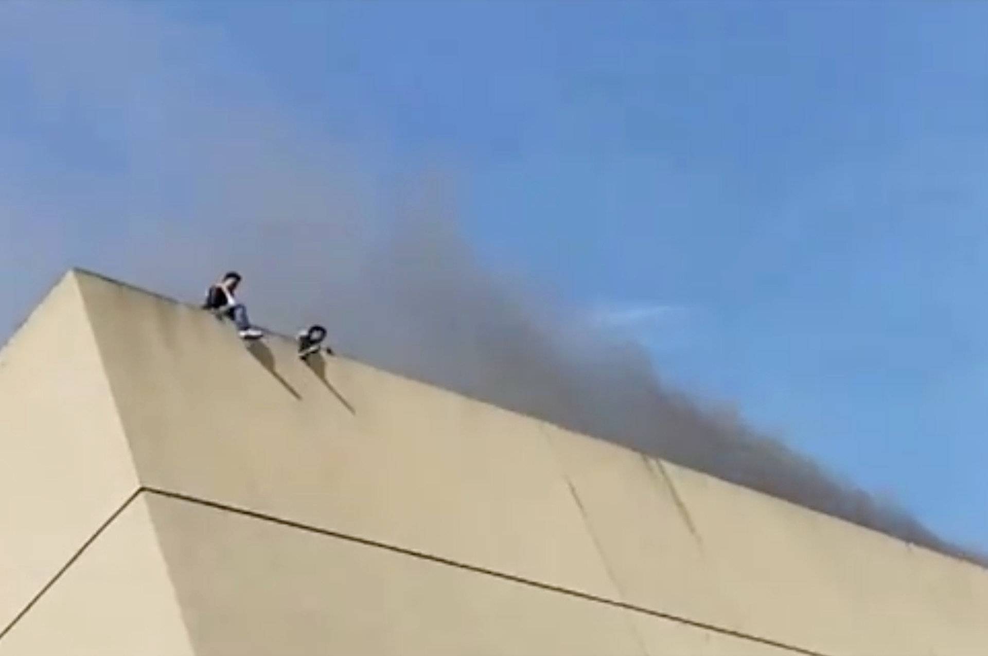 People are seen on the roof of a building as smoke rises during a fire in Davao, the Philippines