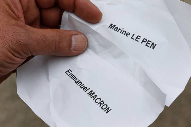 An illustration photo shows a man who holds wrinckled ballots for French presidential election candidates Emmanuel Macron and Marine Le Pen at a polling during the second round of 2017 French presidential election, in Tulle