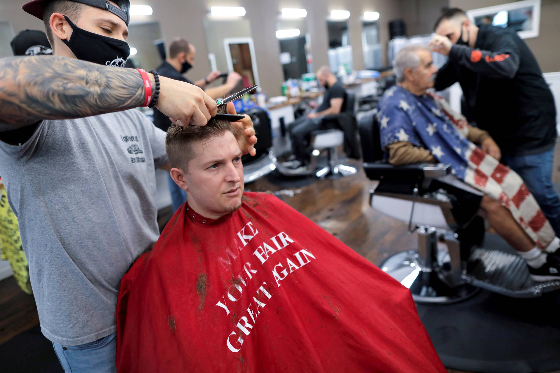FILE PHOTO: Aaron Schumacher, 33, of Staten Island has his hair cut at Craig & Pop's Barbershop while wearing a salon cape with a parody of U.S. President Donald Trump's "Make America Great Again" phrase on Staten Island in New York City