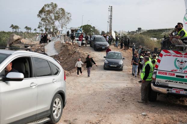 Displaced people cross the bridge linking southern Lebanon to the rest of the country, which was hit earlier in an Israeli strike, in Qasmiyeh