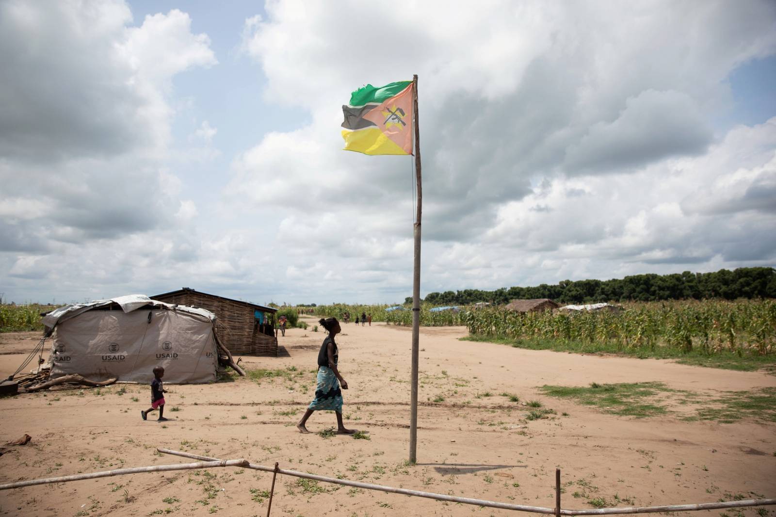 A woman walks past a Mozambique flag in Ndedja resettlement camp in Nhamatanda District, Mozambique
