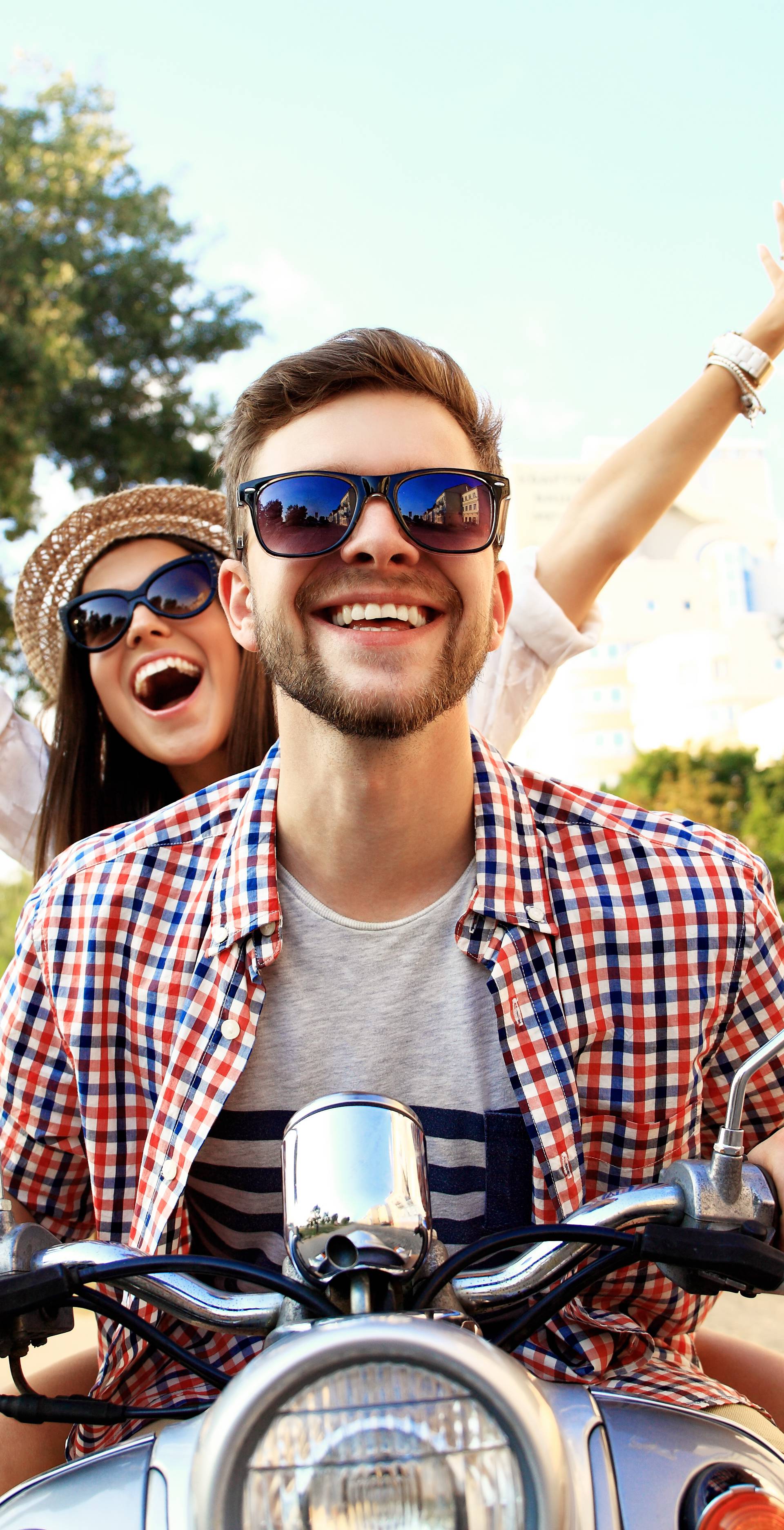 Portrait of happy young couple on scooter enjoying road trip