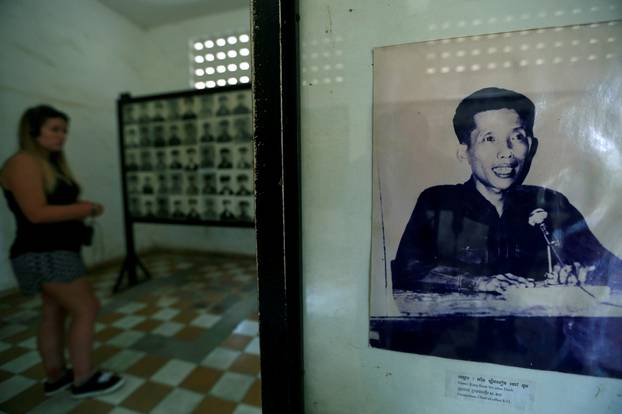 FILE PHOTO: FILE PHOTO: A visitor walks past a picture of Kaing Guek Eav, alias "Duch", who is testifying at an international tribunal