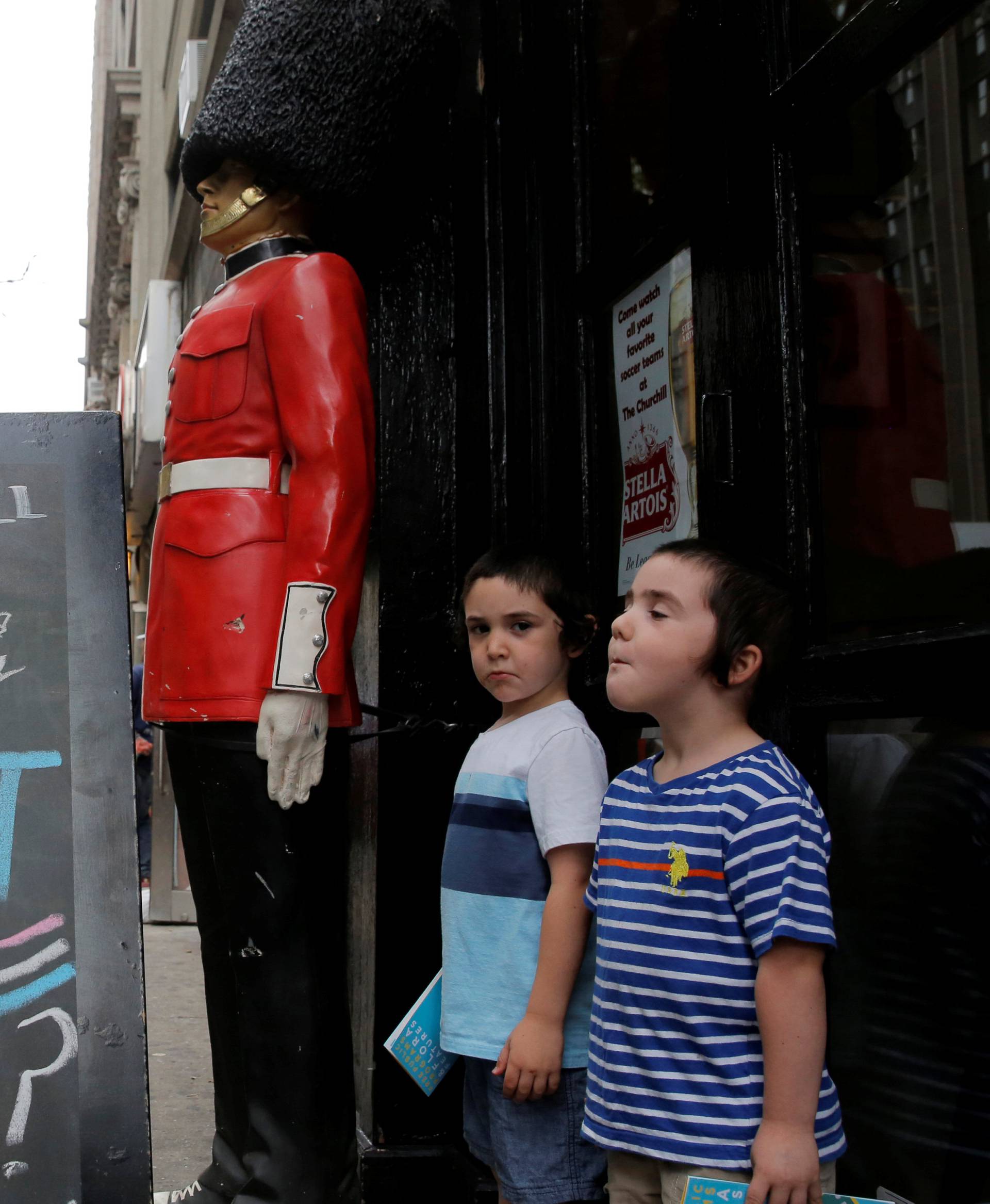 Children pose next to a chalkboard advertising a Brexit viewing event at "The Churchill Tavern", a British theme bar, on the day where Britain votes whether or not to remain in the European Union in the Manhattan borough of New York