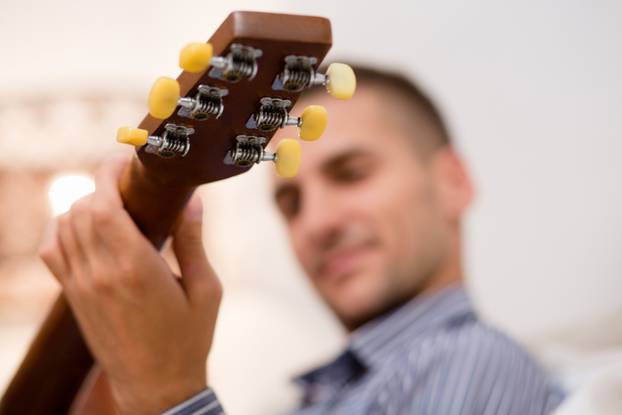 Handsome man playing guitar at home