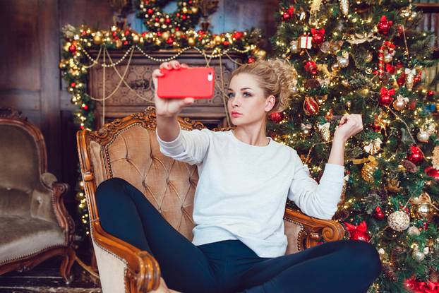 Young pretty blonde woman sitting on a chair near Christmas