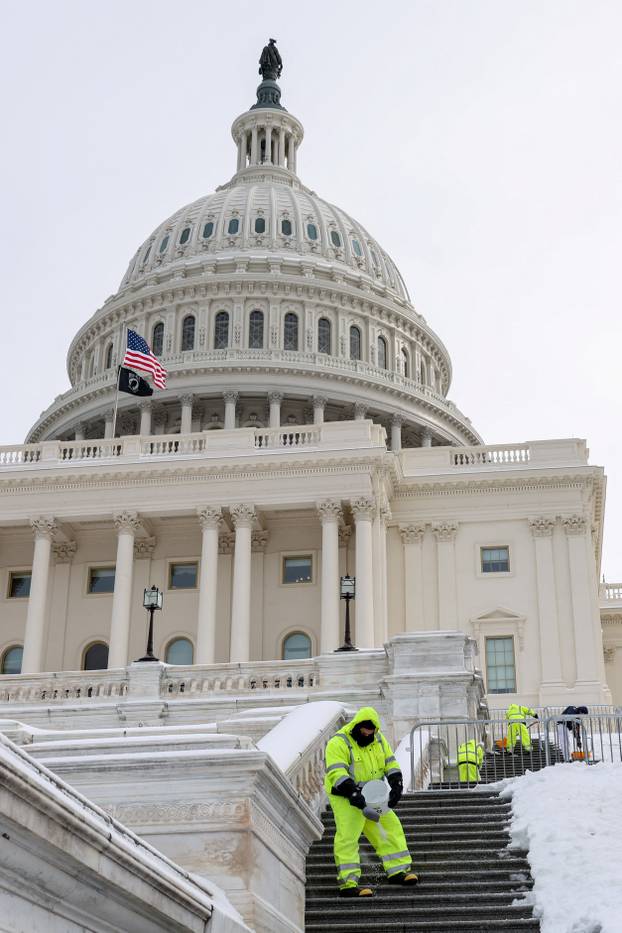 Workers spread salt and shovel the steps of the U.S. Capitol building after a winter storm in Washington