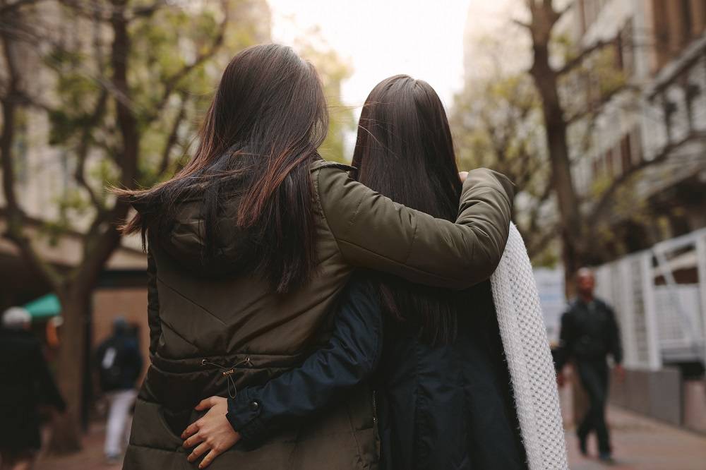 Rear view of two women walking on street