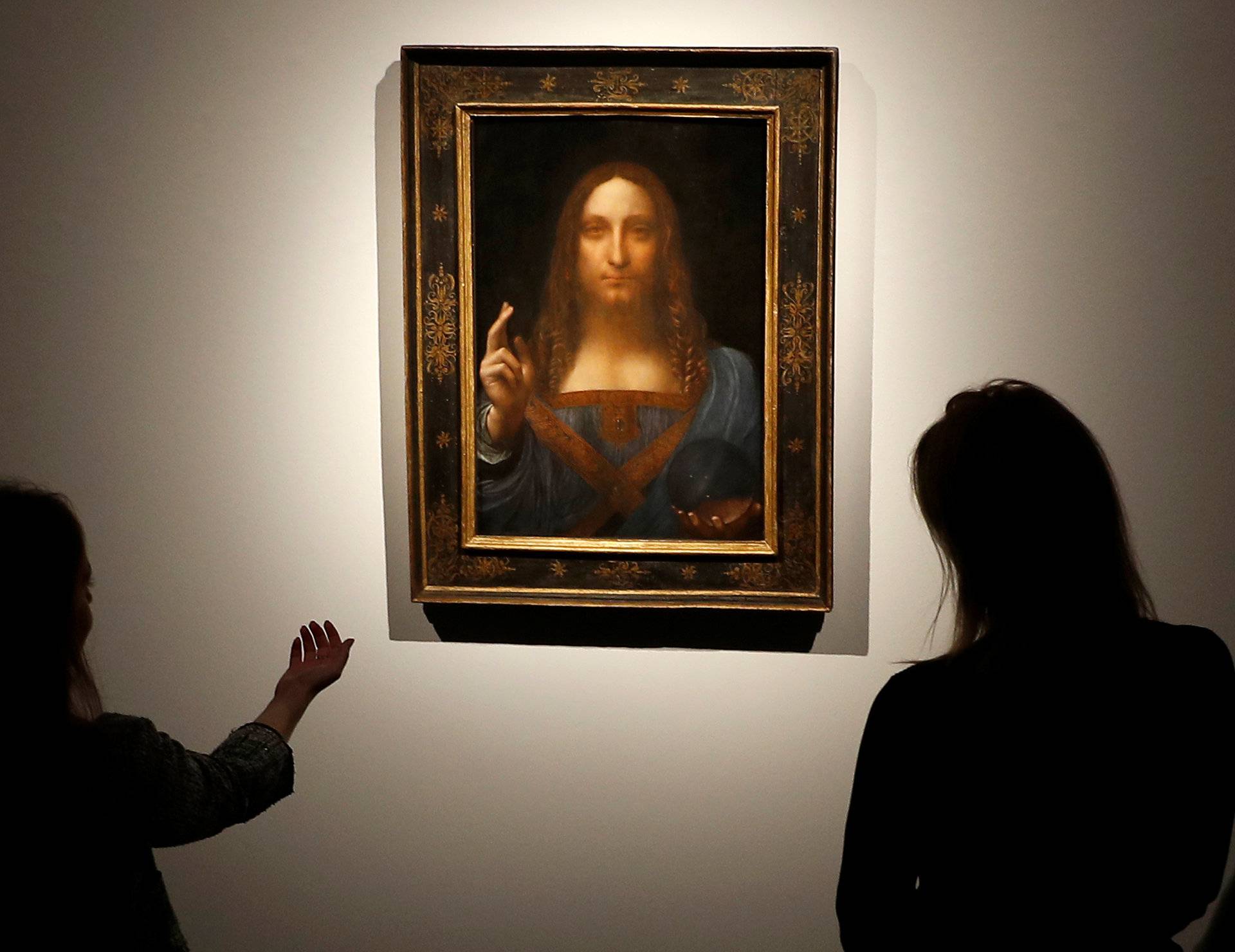 Members of Christie's staff pose for pictures next to Leonardo da Vinci's "Salvator Mundi" painting in London