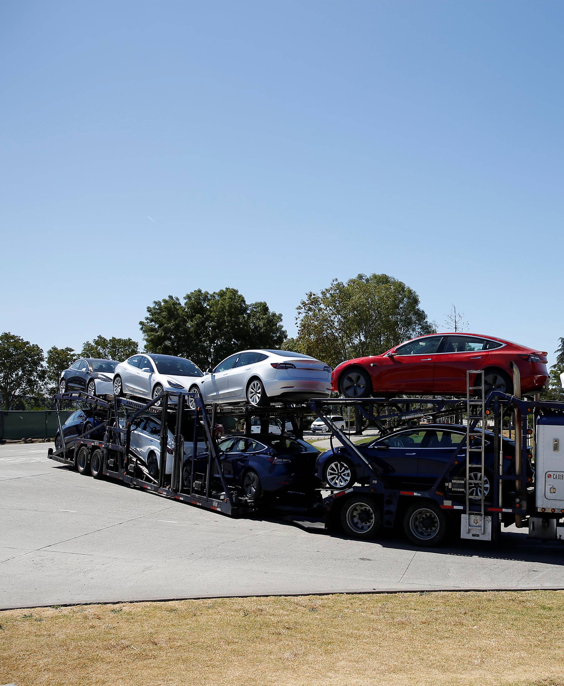 A car carrier trailer carries Tesla Model 3 electric sedans, is seen outside the Tesla factory in Fremont