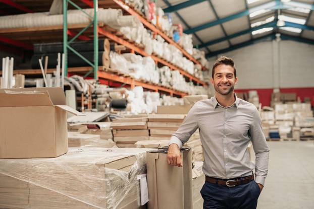 Portrait,Of,A,Smiling,Warehouse,Manager,Leaning,Against,Some,Stock