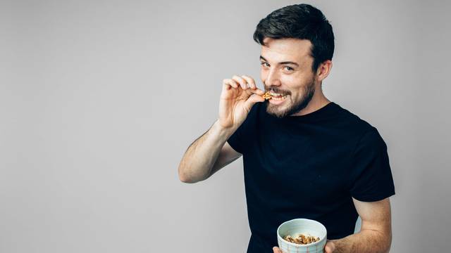 Man,Eats,Nuts,Isolated,On,A,Light,Background.,Man,Shows