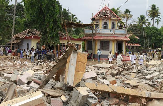 People stand next to debris after a broke out at a temple in Kollam in the southern state of Kerala