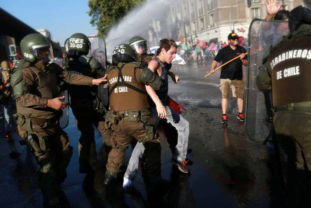 A demonstrator is detained by riot police during a rally in defense of the nationalization of lithium reserves in Santiago