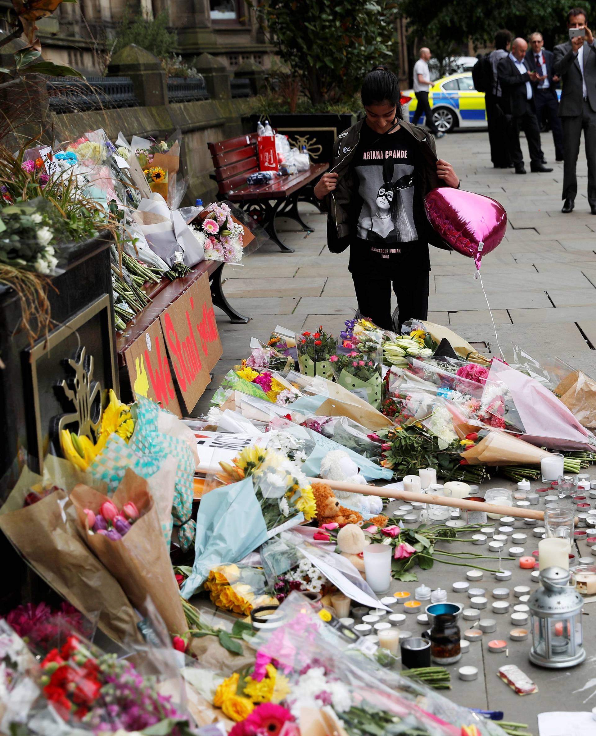 An Ariana Grande fan stands next to floral tributes left for the victims of an attack on concert goers at Manchester Arena, in St Ann's Square, in Manchester