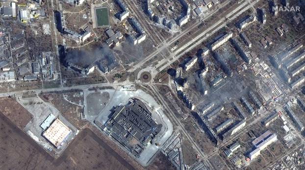 A satellite image shows burning and destroyed apartment buildings and the Port City Shopping Mall in western Mariupol