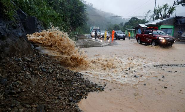 Motorists drive past a partially damaged road after Typhoon Mangkhut hit the main island of Luzon, in Carranglan, Nueva Ecija