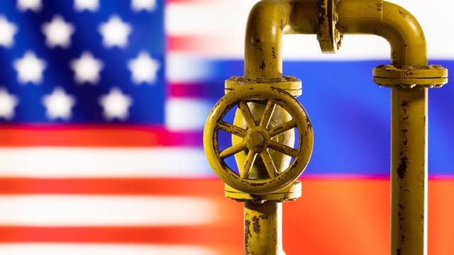 Illustration shows natural gas pipeline in front of word U.S. and Russia flag colours
