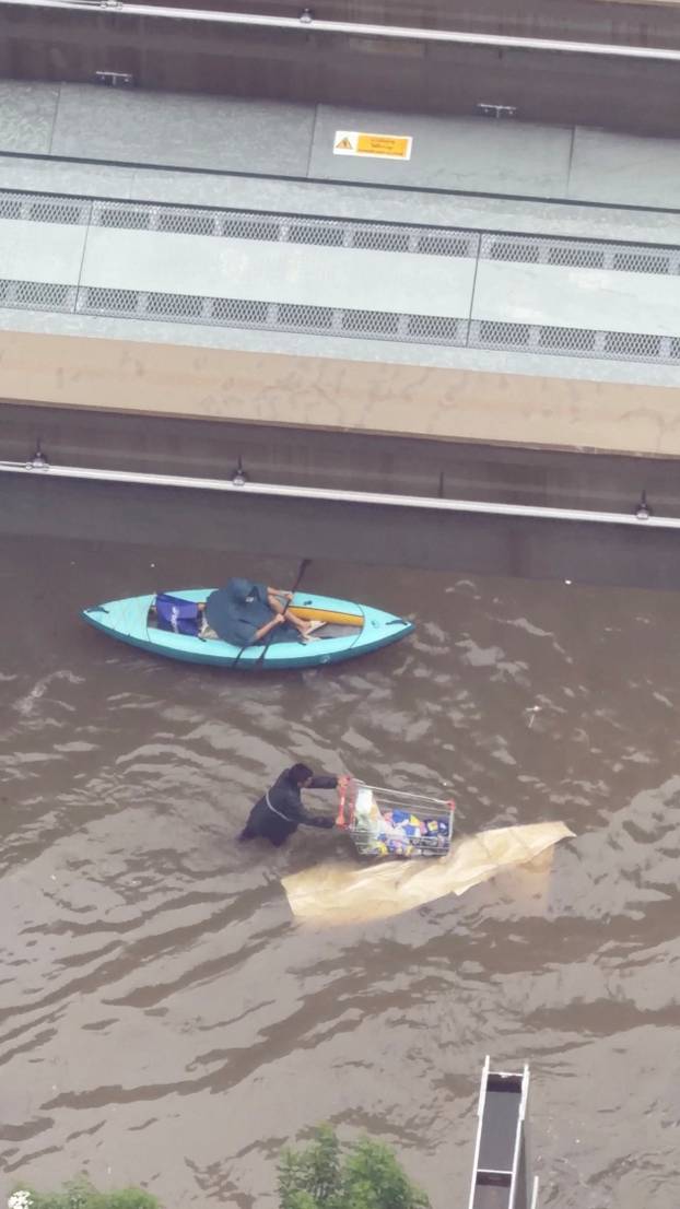 A man pushes a shopping cart as he wades through a flooded following heavy rains, in Bangkok